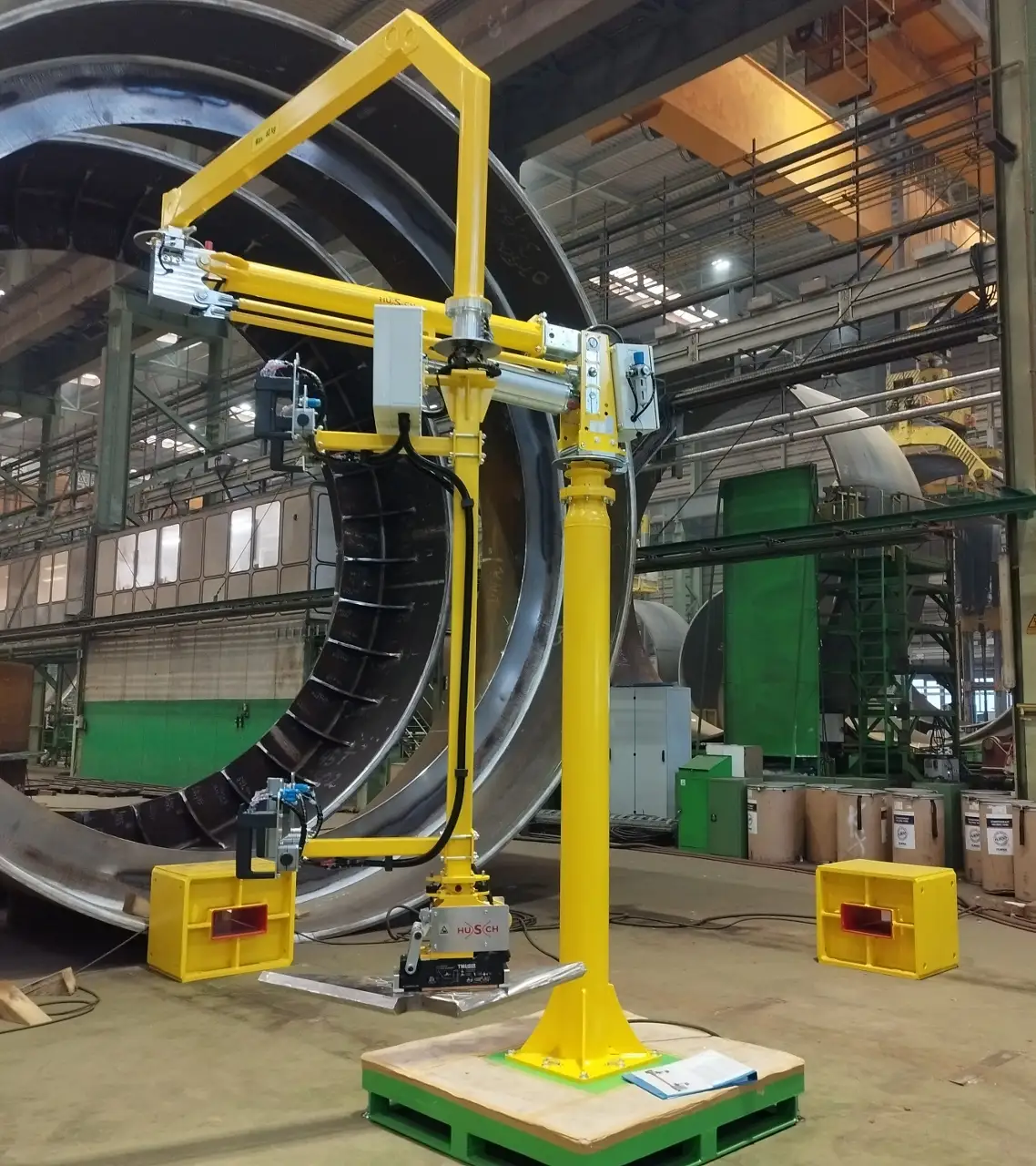 Ein Foto eines gelben Knickarm Manipulators auf Standsäule mit einer magnetischen Aufnahmevorrichtung für Stahlteile