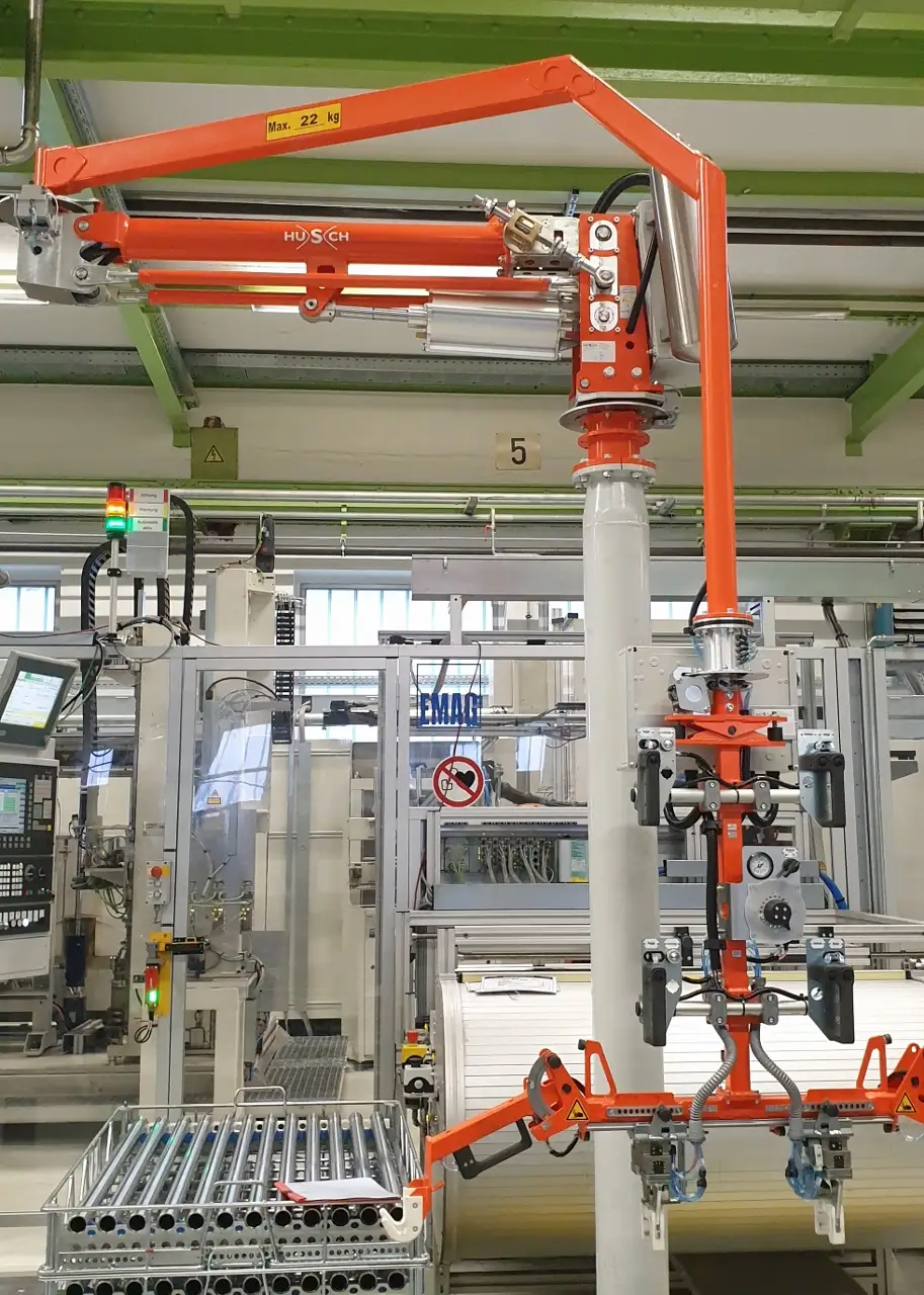 Ein Foto eines orangenen Knickarm Manipulators auf Standsäule einer Aufnahmevorrichtung für Nockenwellen und Gitterkörbe