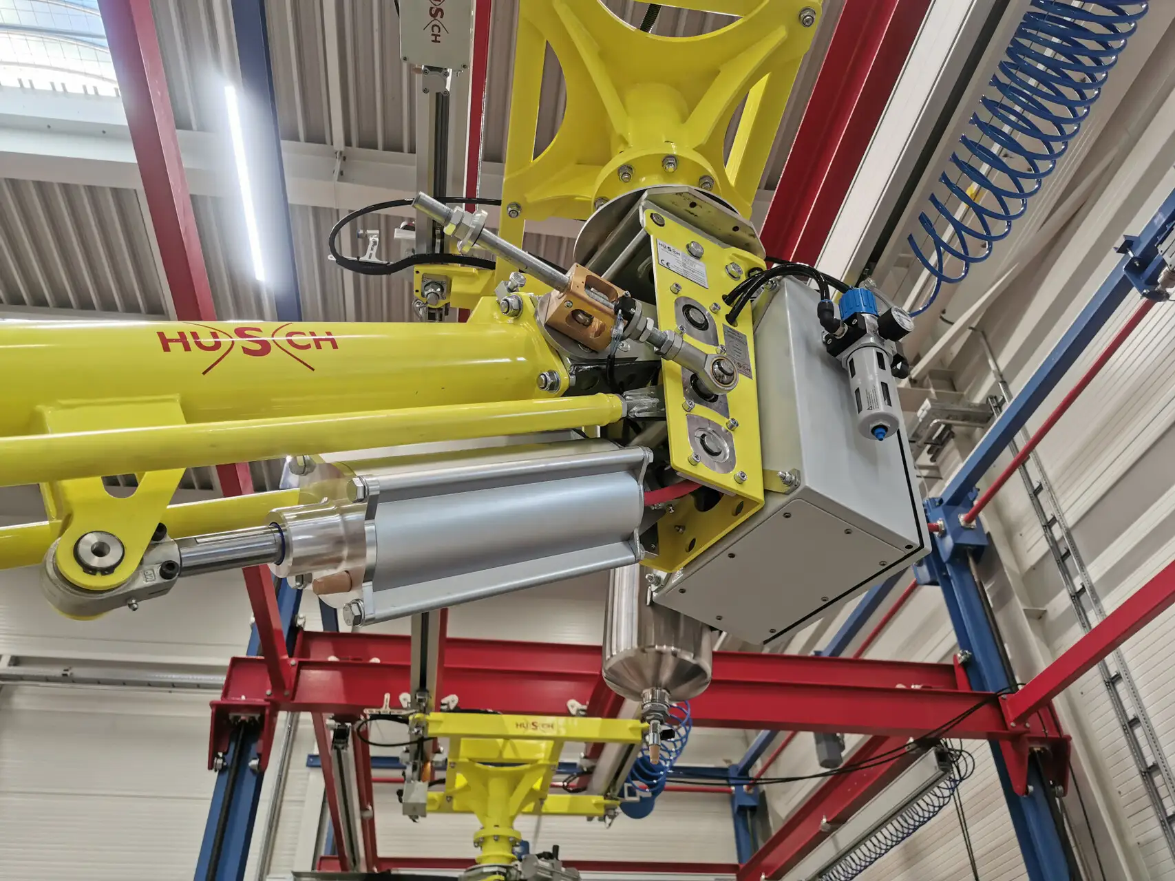 Eine mit gelbe Hubeinheit von einem HUSCH PARALLEL Manipulator in einer Industriehalle