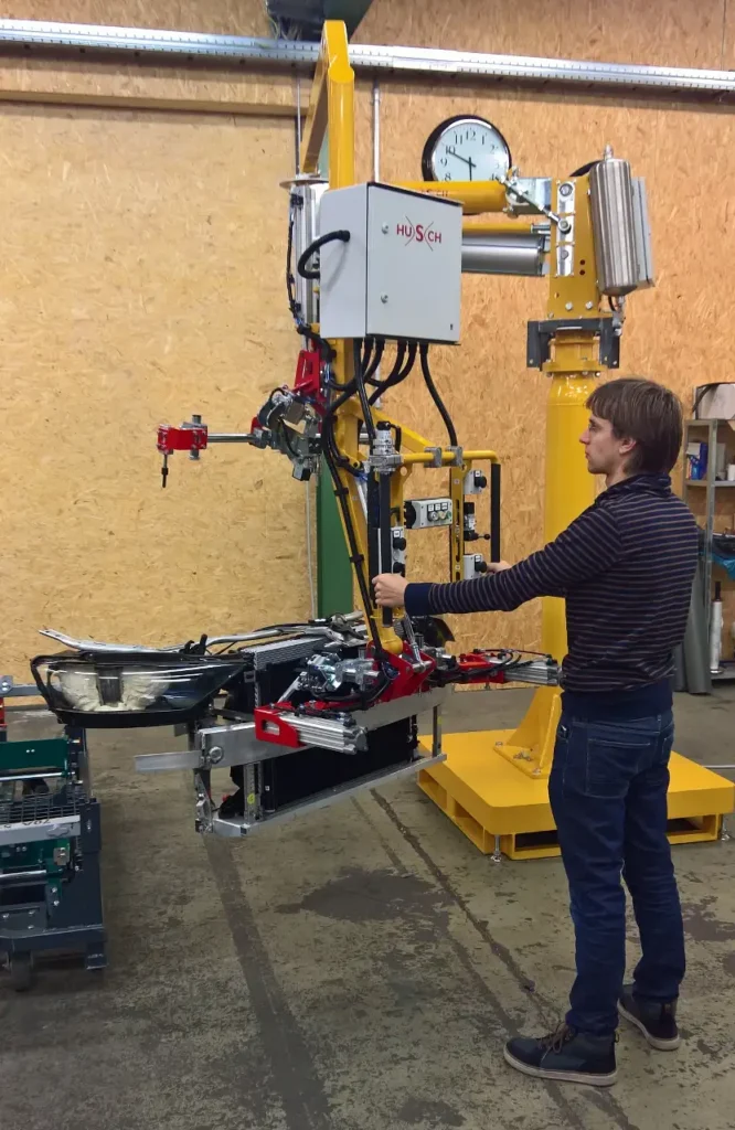 PARALLEL Manipulator for Front-End Modules Ein Foto eines gelben Knickarm Manipulators auf Standsäule mit einem aufgenommenen Frontendmodul.