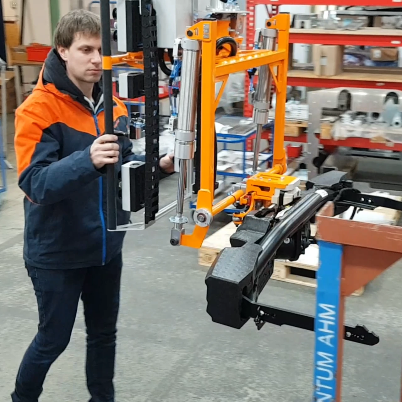 Ein Foto einer orangenen Manipulator Aufnahmevorrichtung mit Bediener und einer aufgenommenen Anhängevorrichtung