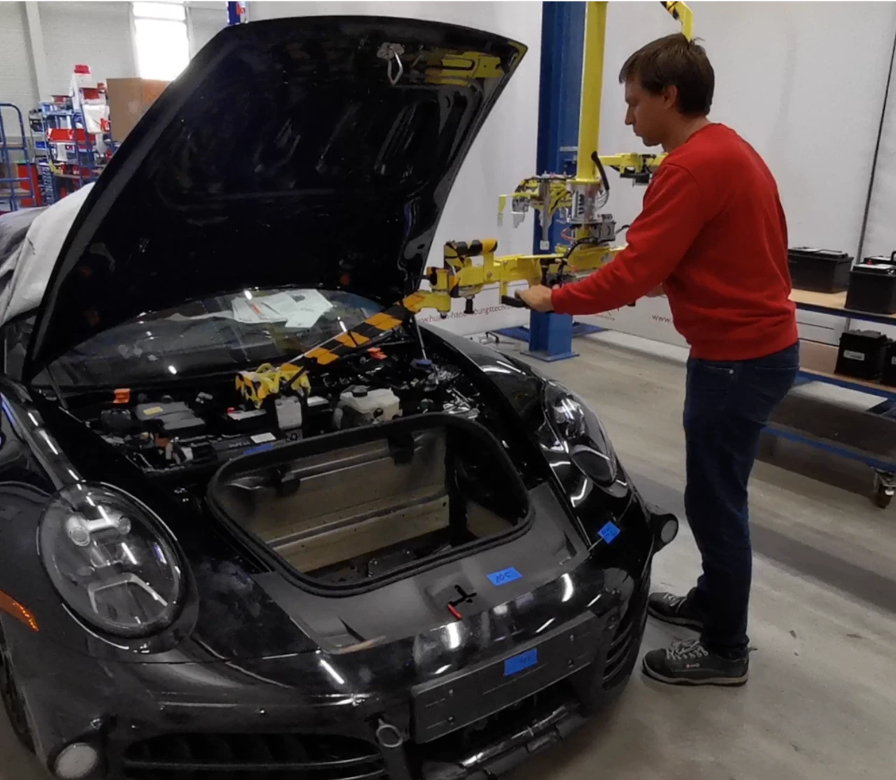 Ein Foto mit einer auskragenden gelben Aufnahmevorrichtung zum Aufnehmen und Einbauen von Batterien in das Fahrzeug.